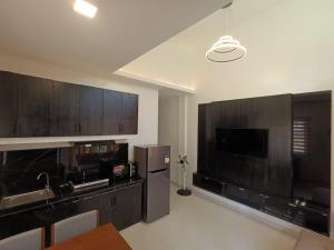 a kitchen with wooden cabinets and a large flat screen tv at Manu-Manu Homestay in Panglao Island