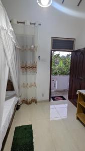 a bedroom with a bed and a window and a door at Villa Dewdrops in Hikkaduwa