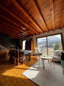 a living room with a table and a large window at Maison montagne vue exceptionnelle En chartreuse in Entremont-le-Vieux