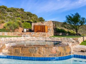 een buitenzwembad met een stenen gebouw met een houten deur bij Ludicks Farm in Montagu