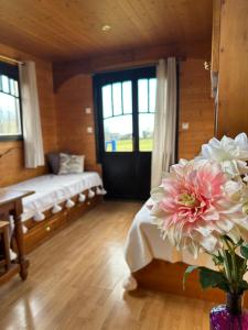 una camera da letto con un letto e una finestra con fiori in un vaso di Les Roulottes des Amis de Wonky a Rétaud
