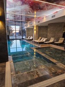 a large swimming pool with chairs in a building at Mokoš apartman, Residence hill A35, minimum dve noći in Kopaonik