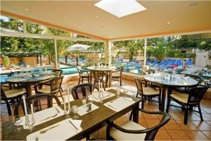 a restaurant with tables and chairs and a swimming pool at Studio on Maria Luisa Beach Wifi Parking Swimming Pool in Olhos de Água