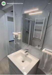 a white bathroom with a sink and a mirror at L'Angolo Del Sorriso in Naples