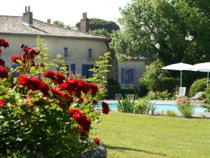 a house and a yard with a pool and red flowers at Chambres d'Hôtes La Sauvageonne in Saint-Palais