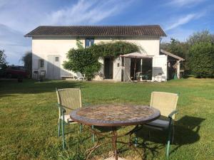 a table and chairs in a yard with a house at Gîte La Louisiane in Salies-de-Béarn