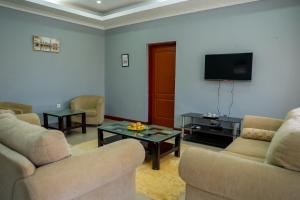 a living room with couches and a flat screen tv at Downtown Oasis Suites in Lilongwe