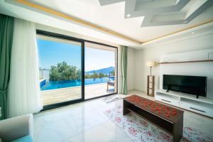 a living room with a tv and a large window at KaşKalkan Deniz manzaralı Havuzlu Bahçeli Villa in Kas