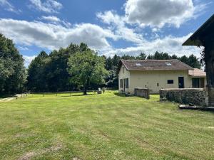 an old house with a large grass field in front of it at Maison dans les bois in Lacquy