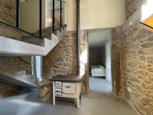 a room with a stone wall with a table and a staircase at Casa La Pedrosa - Tedin in Cee