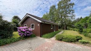 a smallshed with pink flowers in front of it at Ferienhaus mit drei Schlafzimmern Nähe Freizeitpark Schloss Dankern Dankernsee in Düne