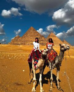 two women riding on camels in front of the pyramids at Horus pyramids view in Cairo