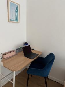 einen Schreibtisch mit einem Laptop und einem blauen Stuhl in der Unterkunft APPARTEMENT CENTRE VILLE AVEC TERRASSE ET PARKING SECURISE in Rennes