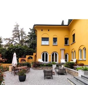 a yellow building with chairs and tables in a courtyard at Villa Ella con Depandance in Gardone Riviera