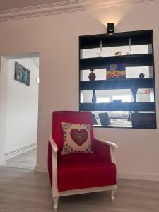 a red chair with a heart pillow in a room at Central Park Bragadiru Loft in Bragadiru