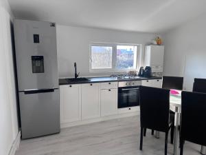 a kitchen with a refrigerator and a table with chairs at Central Park Bragadiru Loft in Bragadiru