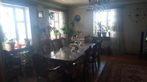 una sala da pranzo con tavolo, sedie e finestre di Дом гостевой Для семьи a Sevan