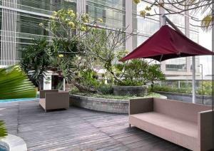 Studio Almahyra Alana Jogja في Kejayan: فناء مع مقعد ومظلة في مبنى