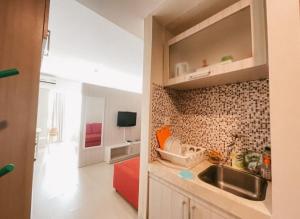 Studio Almahyra Alana Jogja في Kejayan: مطبخ مع حوض وأريكة حمراء