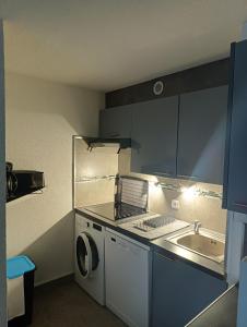 eine kleine Küche mit einer Waschmaschine und einem Waschbecken in der Unterkunft Mer et dune - Les Caravelles in Saint-Cyprien