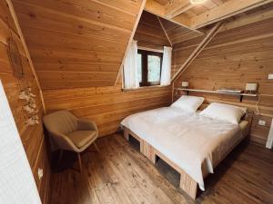 a bedroom in a log cabin with a bed and a chair at Basikowe Wzgórze, 2 domki z kominkami i jacuzzi in Korbielów