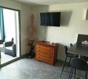 un salon avec une commode et une télévision murale dans l'établissement Logement plage, à Saint-Cyprien
