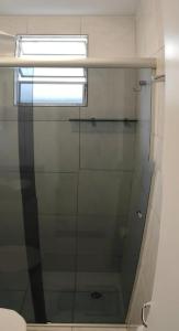 a glass shower door in a bathroom with a window at Apto 2 quarto completo com vaga-proximo shopping contagem in Contagem +7 photos