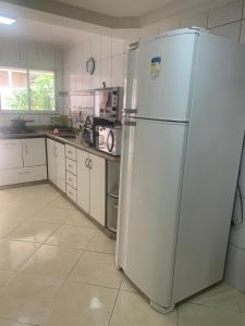 a kitchen with a white refrigerator in a room at Apto no centro comercial de guriri, 2 garagens andar térreo in São Mateus +9 photos