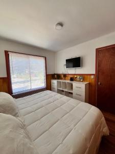 ein Schlafzimmer mit einem großen weißen Bett und einem Fenster in der Unterkunft Cabaña estilo mediterránea in Pucón