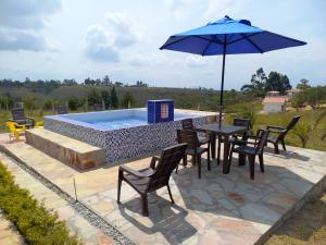 洛斯桑托斯Cabañas GARUTO的一张桌子、几把椅子、一把遮阳伞和一个游泳池