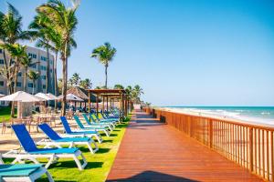 a boardwalk leading to the beach with chairs and umbrellas at Costeira Palace Beach Resort All Inclusive in Natal