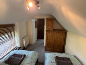 a attic room with two beds and a cabinet at May Cottage in Tideswell