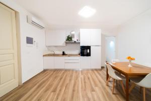 a kitchen and dining room with white cabinets and a wooden table at La dimora di via Umberto in Catania +35 photos