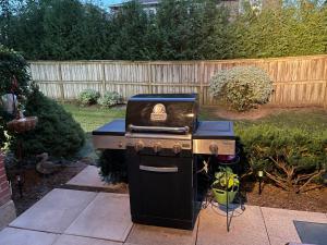 a barbecue grill in a backyard with a fence at Welcoming homestay with relaxing private room in Oakville