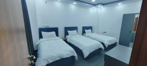 Motel beyza في السليمانية: غرفة بها ثلاثة أسرة مع ملاءات بيضاء
