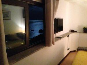 a room with a window with a television and a couch at B&B La Terrazza Sul Mare Taormina in Taormina