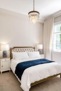 a white bedroom with a large bed and a chandelier at Cape Loader House in Cape Town