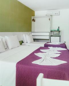 two beds in a room with a purple blanket at Pousada Ouriço in Porto De Galinhas +87 photos