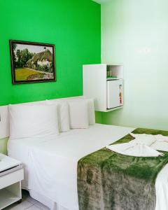 Un dormitorio con una cama blanca con una pared verde. en Pousada Ouriço, en Porto de Galinhas