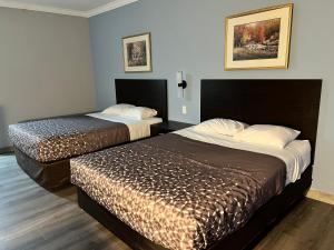 Tahlequah Inn في تاهليكوا: غرفة فندقية تحتوي على سريرين في الغرفة