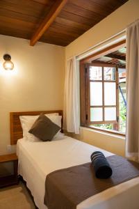 una camera da letto con un letto e una finestra di Hotel Pousada Villa Zena - Frente ao Mar - Pé na areia a Arraial d'Ajuda