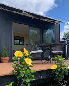 a black tiny house with yellow flowers on a deck at Stunning Coastal Olive Grove in Mangonui