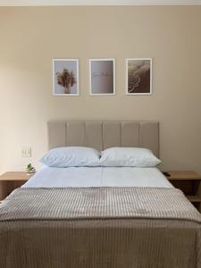 a bedroom with a bed with four pictures on the wall at Suíte de Casal Privativa com Sacada in Sao Jose do Rio Preto