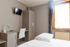 a bedroom with a bed and a desk and a monitor at Albergo Montenegro in Maniago
