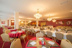 une salle de banquet avec des tables, des chaises et des lustres dans l'établissement Hotel Slovan, à Tatranská Lomnica