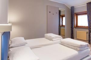 two beds in a room with white walls and a mirror at Albergo Montenegro in Maniago