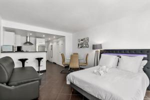 a bedroom with a bed and a chair and a kitchen at Luxury Studio YourHostHelper in Cannes