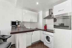 a kitchen with white cabinets and a washer and dryer at Luxury Studio YourHostHelper in Cannes
