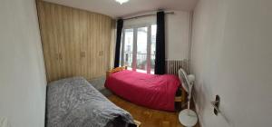una camera da letto con un letto rosso e una finestra di Appart à Maisons Alfort en plein centre ville à 5 min de la Gare Rer a Maisons-Alfort