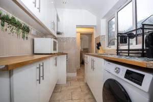 a kitchen with white cabinets and a washer and dryer at 2Bed Mid Terrace Close To Station in Stoke on Trent